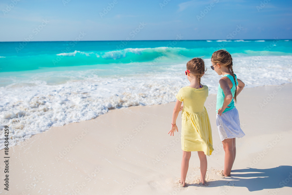 Little girls at tropical beach playing together on the seashore
