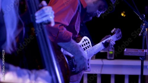 Closeup of a roots musician rocking out on a resonator guitar at night at a restaurant.