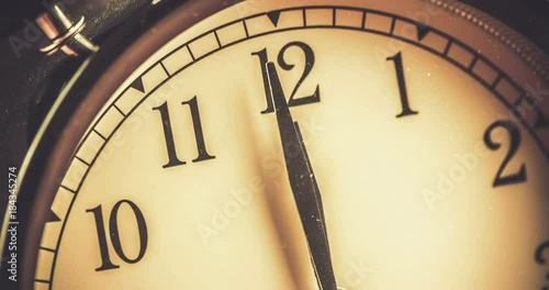 old grunge vintage alarm clock is showing midday or midnight movement. It is twelve o'clock, holiday happy new year festive and christmas or lunch concept, time-lapse effect