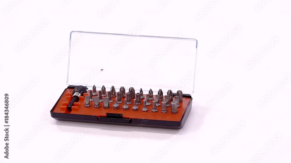 screwdriver set with bits in small open box is standing on a white rotating table, close-up screwdriver set with bits in small open box is standing on a white rotating table, close-up