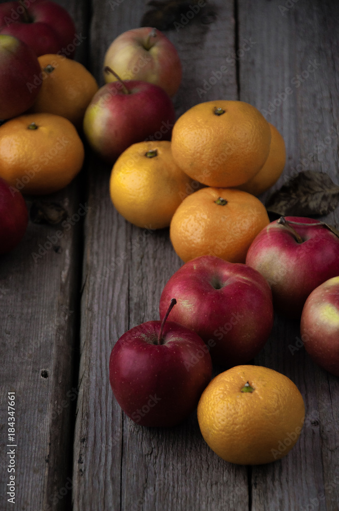 On a wooden table scattered fresh mandarins and red apples On a wooden table scattered fresh mandarins and red apples