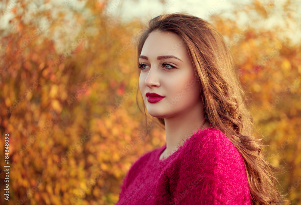 Portrait of an young attractive woman with long brown hair enjoying her time in the autumn park with yellow tree in background Portrait of an young attractive woman with long brown hair enjoying her time in the autumn park with yellow tree in background