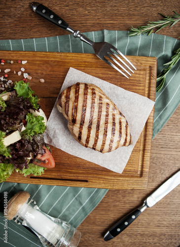chicken grilled breast with fresh salad and tomatoes on a wooden board