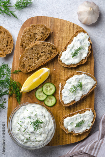 Homemade greek tzatziki sauce in a glass bowl with ingredients a