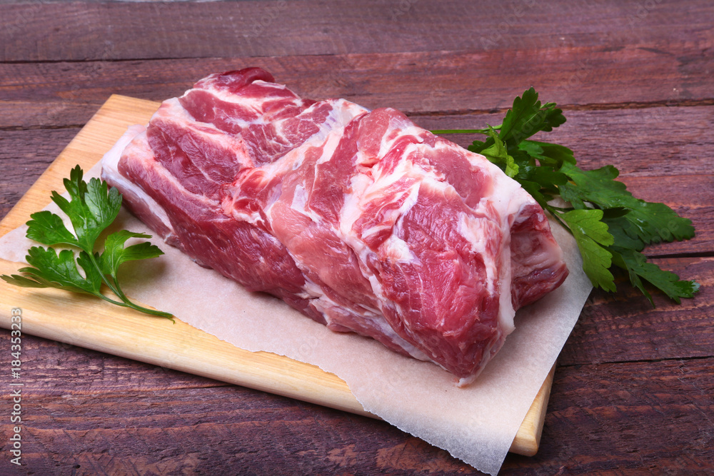 Raw pork neck chop meat with parsley herb leaves on a stone background. Ready for cooking. Raw pork neck chop meat with parsley herb leaves on a stone background. Ready for cooking.