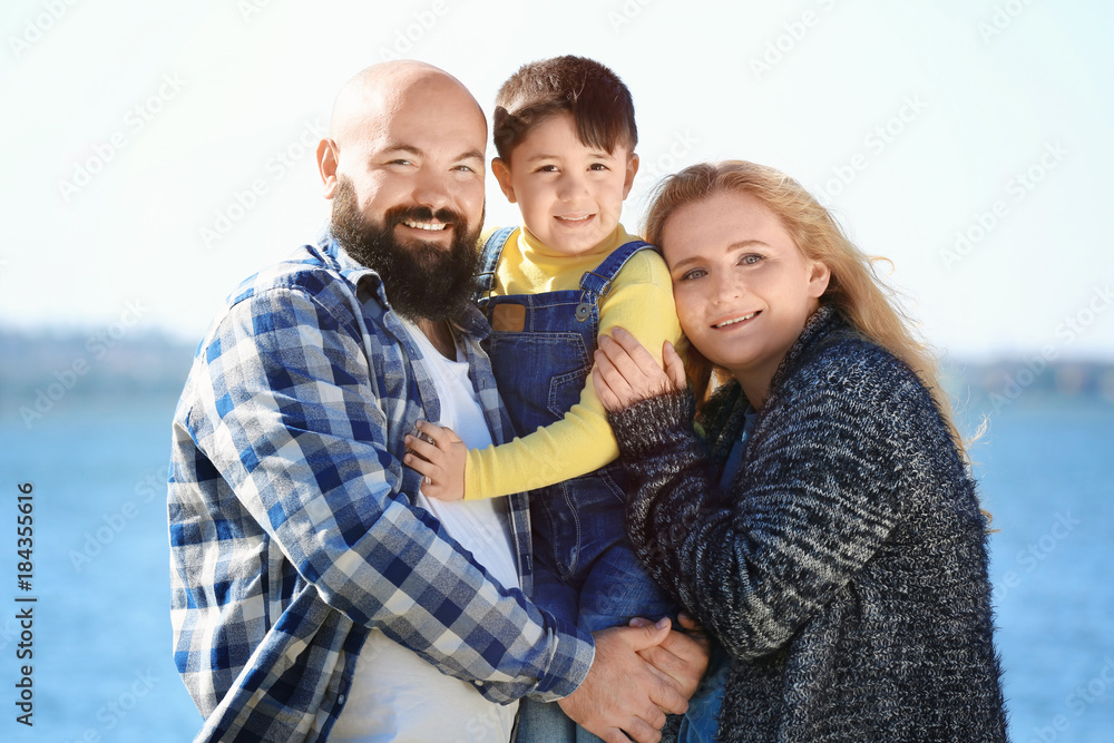 Overweight couple with son near river on sunny day Overweight couple with son near river on sunny day