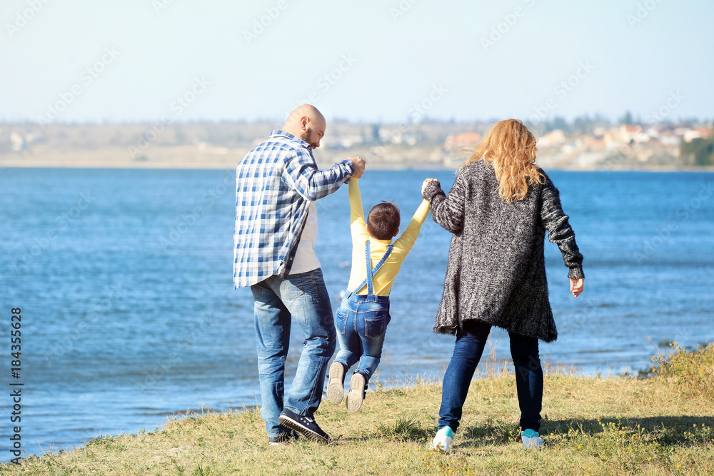 Overweight couple with son walking near river on sunny day Overweight couple with son walking near river on sunny day