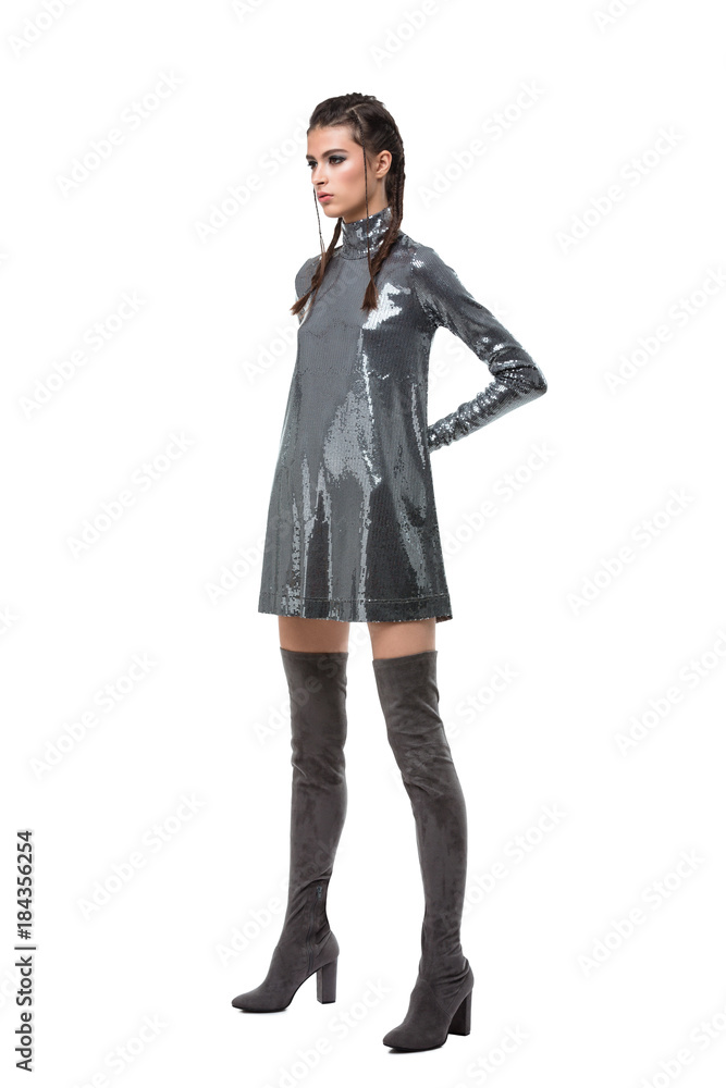 Young pretty lady standing in dress in sequins and knee high boots on white background Young pretty lady standing in dress in sequins and knee high boots on white background
