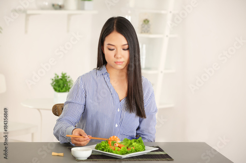 Beautiful Asian woman eating shrimps at table