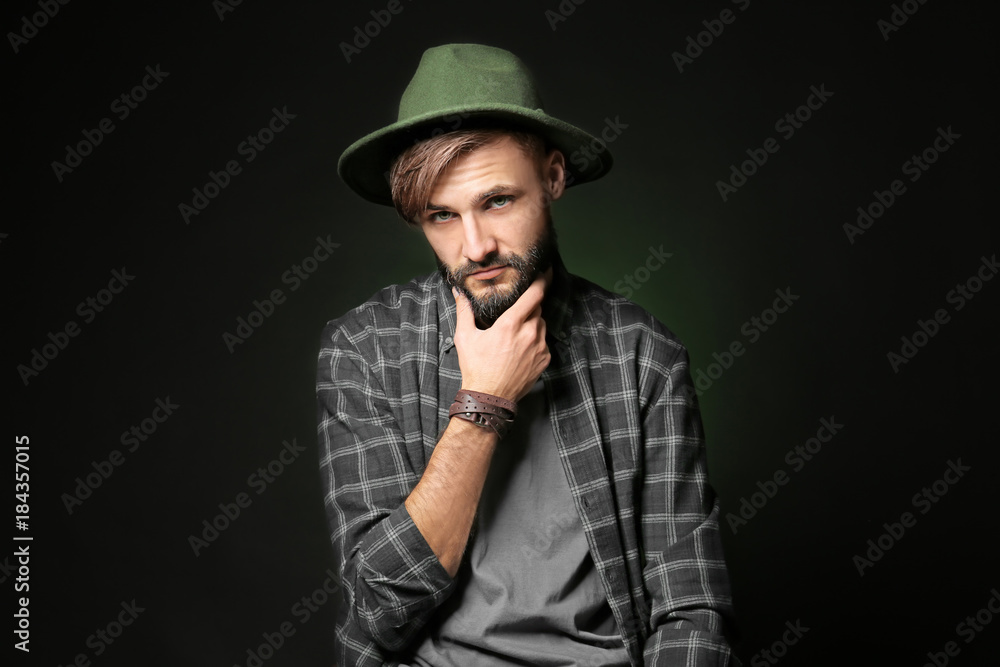 Thoughtful young hipster man on dark background Thoughtful young hipster man on dark background