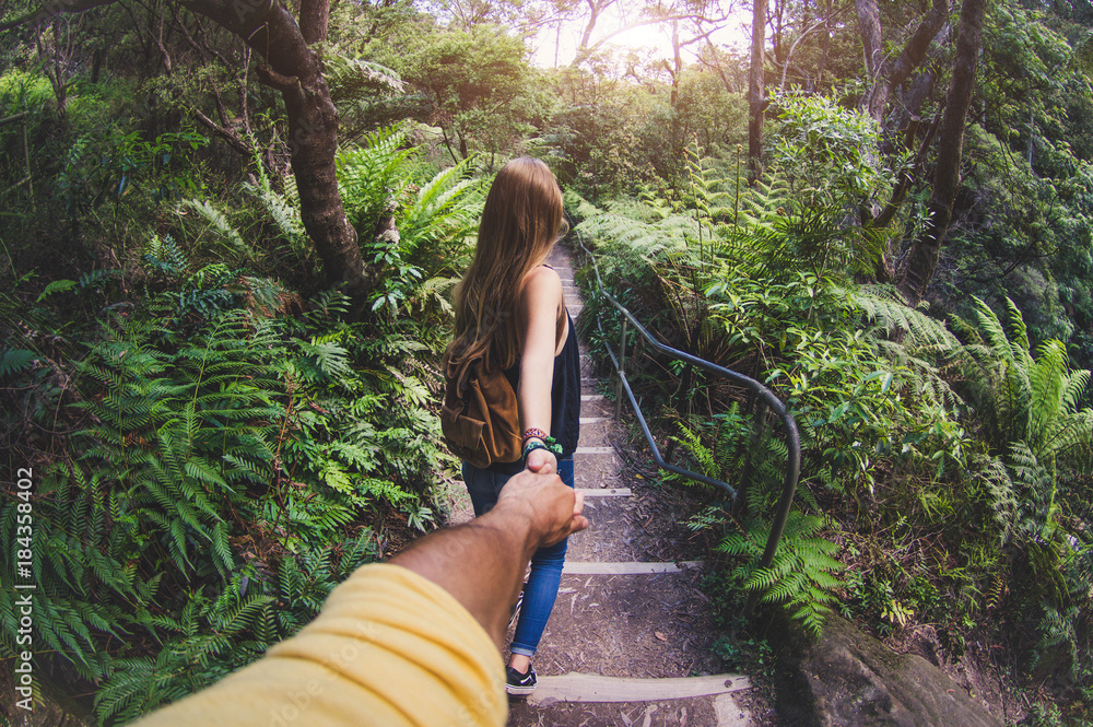 Closeup Young woman holding man hand while leading him on nature
