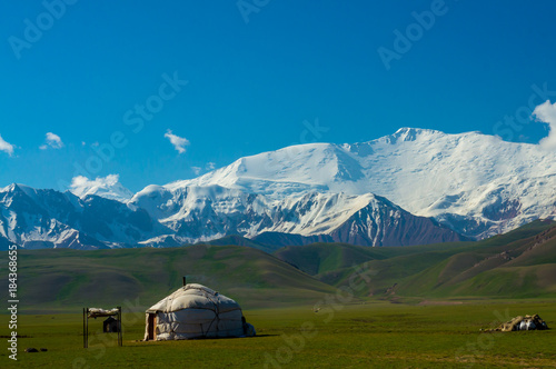 Majestic mountains in Chon-Alai and kyrgyz yurt under the peak of Lenin and a blue sky with clouds photo