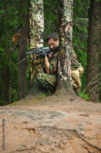 soldier aiming a machine gun in the woods