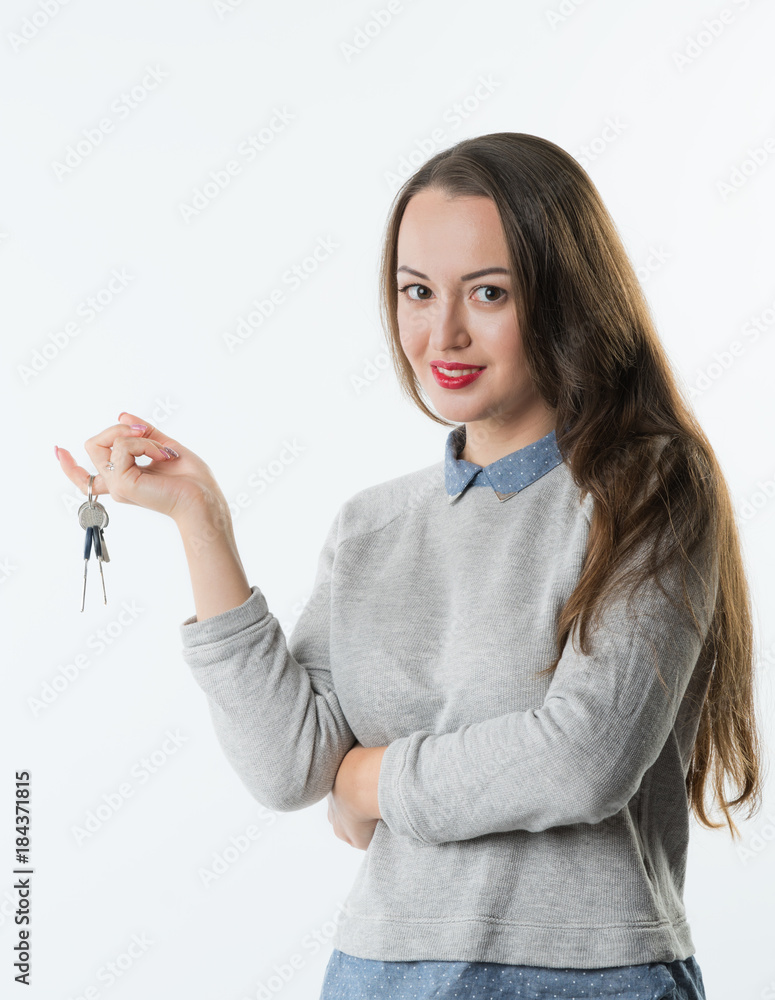 Young pretty smiling business woman or real estate agent with keys from new flat or house on the finger. She welcomes to buy a flat or house. Young pretty smiling business woman or real estate agent with keys from new flat or house on the finger. She welcomes to buy a flat or house.