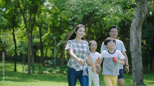 Chinese family smiling & walking together in park