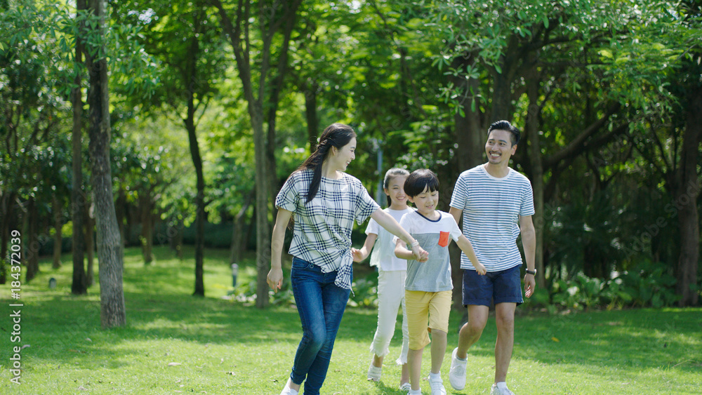 Chinese family smiling & walking together in park Chinese family smiling & walking together in park