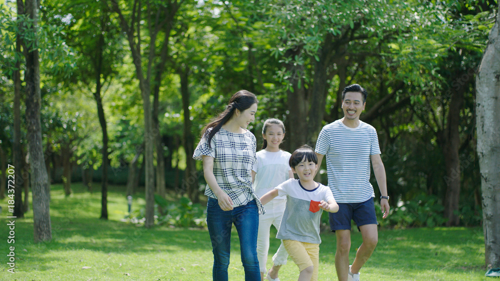 Chinese family smiling & walking together in park Chinese family smiling & walking together in park