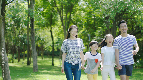 Chinese family smiling & walking together in park © allensima