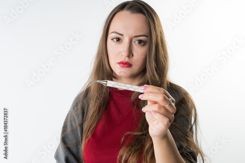 sick woman checking her temperature with thermometer . She has cold and fever, isolated on white background photo