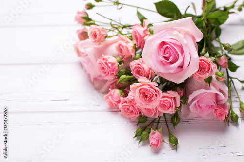 Tender pink roses flowers on white wooden background.