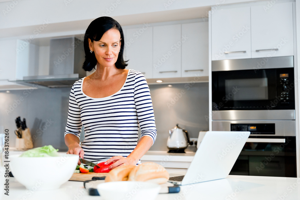 Beautiful woman standing in the kitchen and cooking