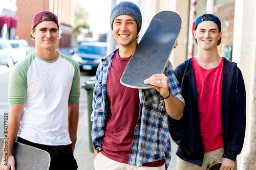 Teenage friends walking at the street with skateboards