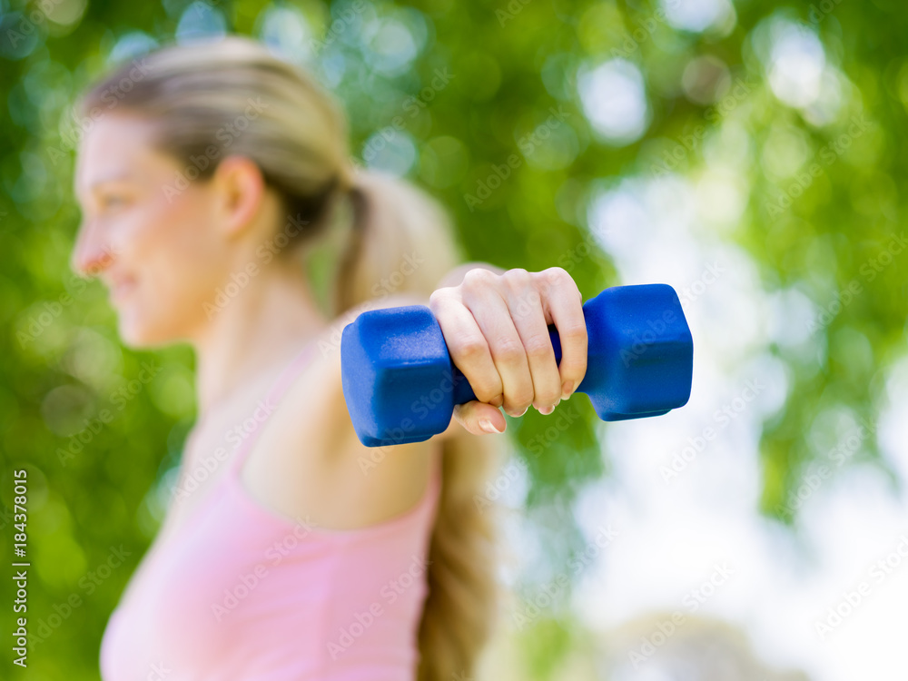 Portrait of cheerful woman in fitness wear exercising with dumbbell Portrait of cheerful woman in fitness wear exercising with dumbbell