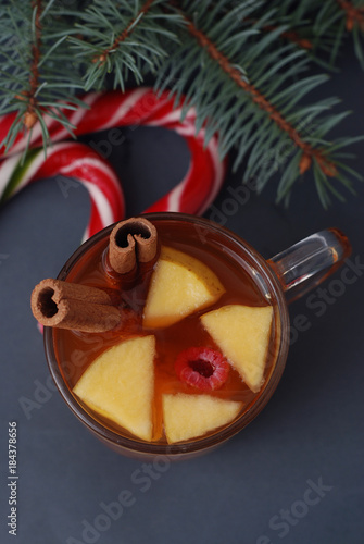 Hot Winter Tea with Fruits - apple, cinnamon, anise. On Dark marble table. Cristmas Candy, Fir Branches. Ttop view photo