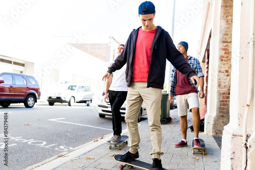 Teenage friends walking at the street with skateboards