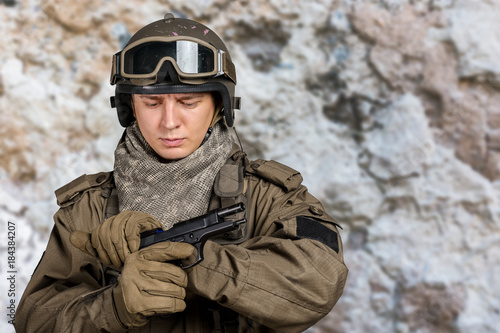 Young man in military uniform checking revolver gun © fotofabrika