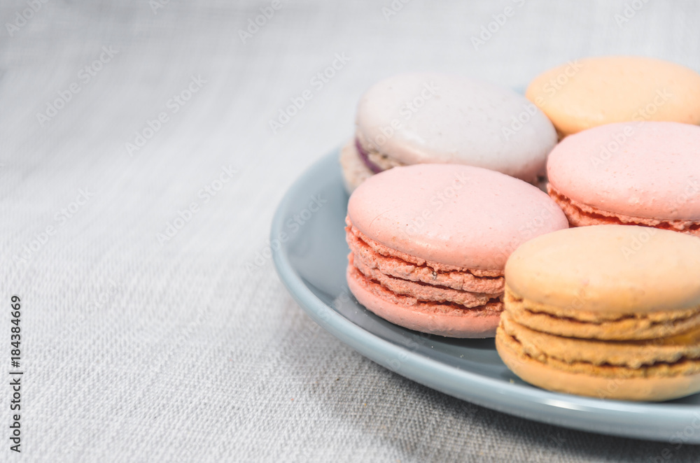 Delicious cake macaroons on plate on light background, close up Delicious cake macaroons on plate on light background, close up