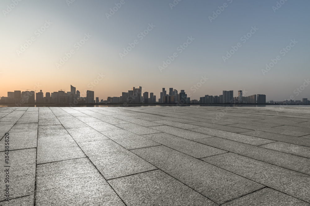 empty brick floor with cityscape and skyline at twilight.