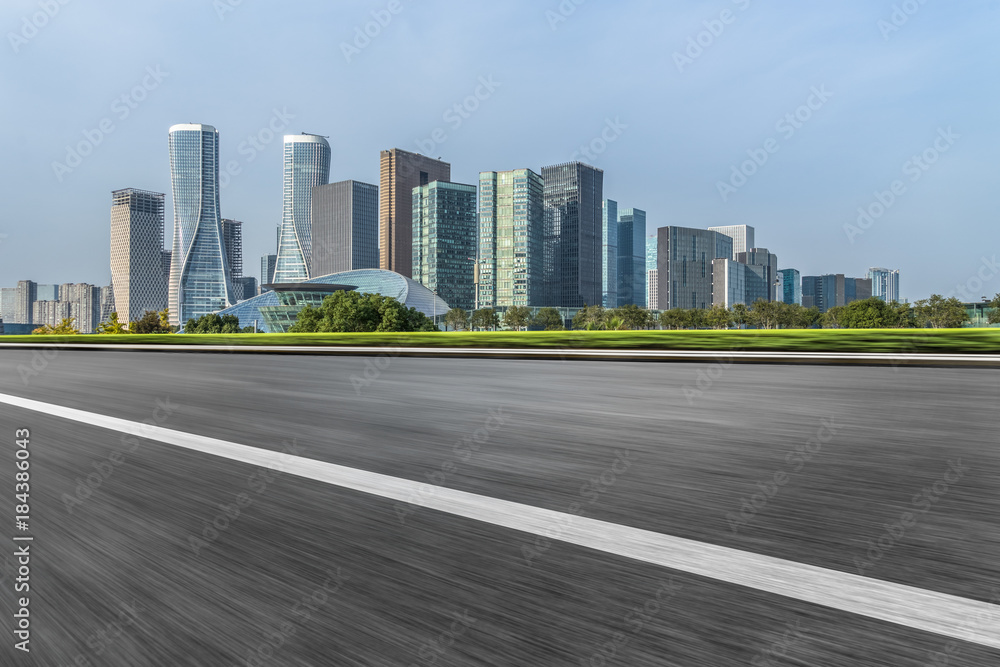 blurry empty asphalt road and cityscape against blue cloud sky