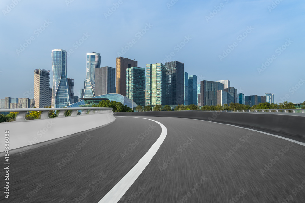 blurry empty asphalt road and cityscape against blue cloud sky