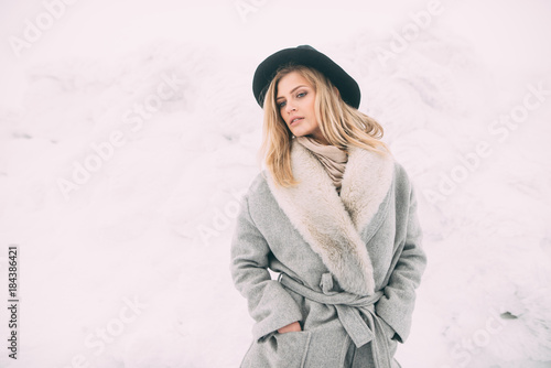 Beautiful winter portrait of young woman in the winter snowy scenery.