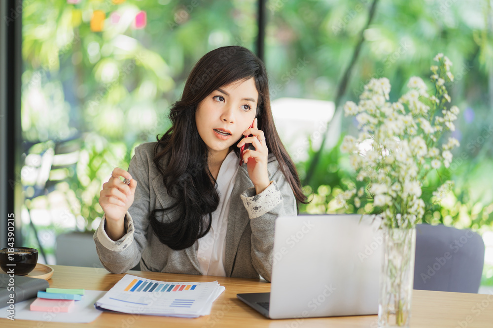 Portrait of an attractive young woman holding her phone while working in coffee shop. Portrait of an attractive young woman holding her phone while working in coffee shop.