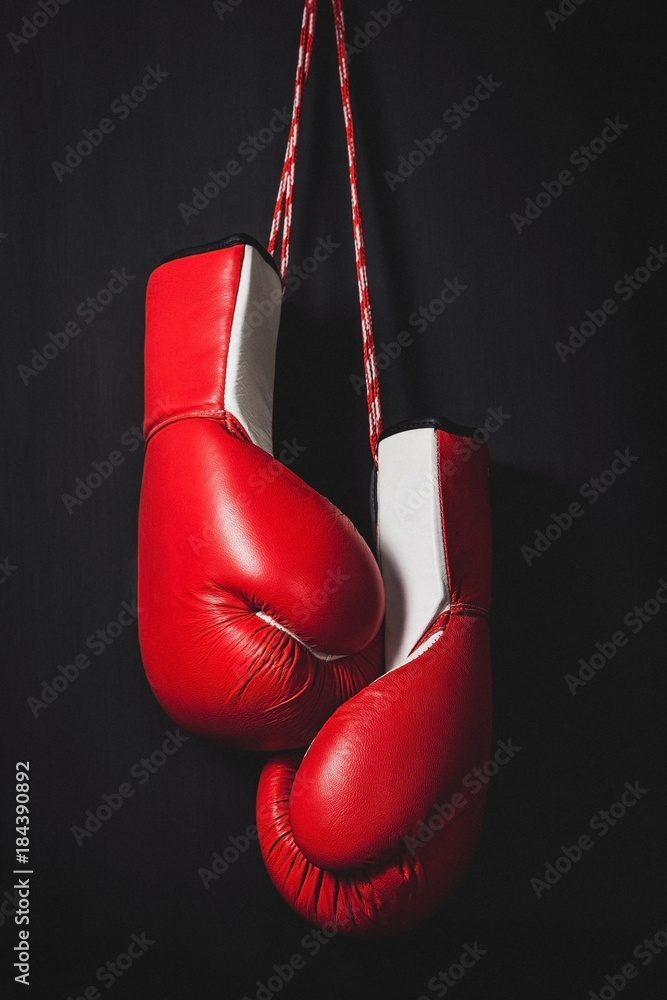 Professional red boxing gloves hanging on black background with copy space.