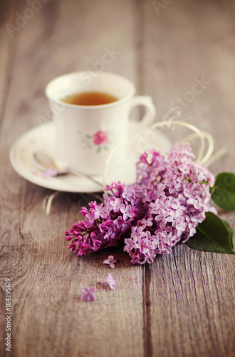 Tazza di tè su tavolo in legno con fiori di lillà. Immagine romantica