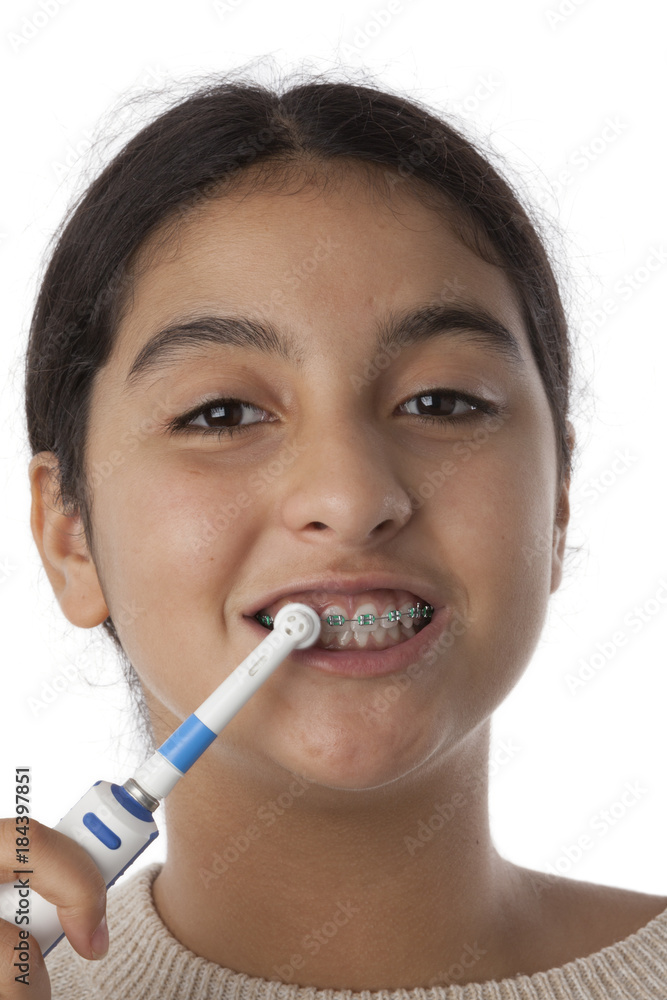Teenage girl is brushing her teeth with dental braces Teenage girl is brushing her teeth with dental braces