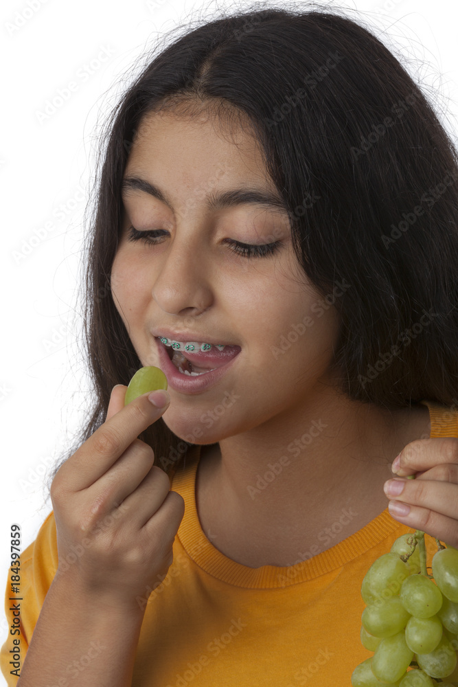 Teenage girl with dental braces eating grapes Teenage girl with dental braces eating grapes