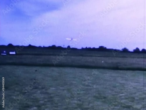 Radio controlled airplane pilot taxis his plane down grassy runway and takes off into the sky for aerobatic maneuvers at the Bridgewater state farm correctional institution in Fall 1967