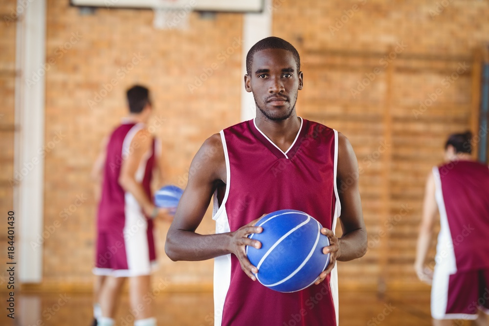 Confident  basketball player holding a basketball