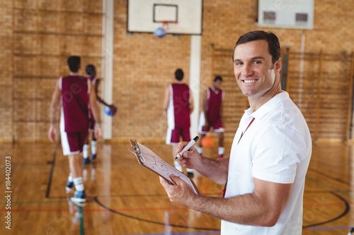 Obraz na plátně Basketball coach holding clipboard in the court