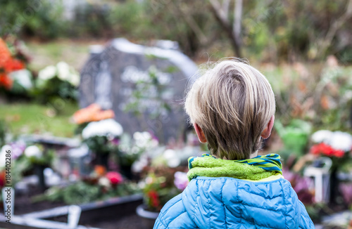 Fotografie Little boy standing at the grave of his parents