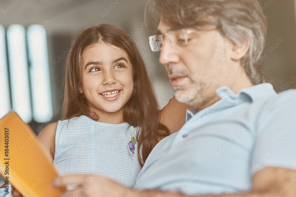 Pleasant caring father reading a book with his daughter Pleasant caring father reading a book with his daughter