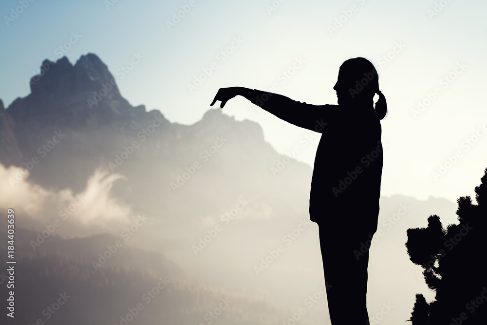 Eine Frau im Nebel zeigt auf die Berge