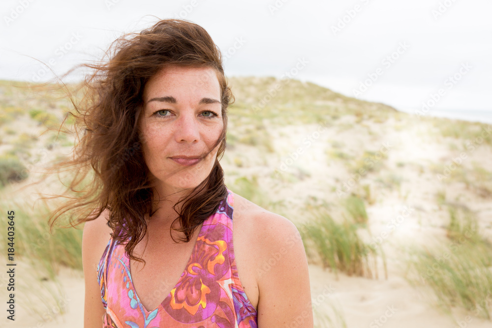 beautiful woman with hair in the wind on the sand dune during summer vacation