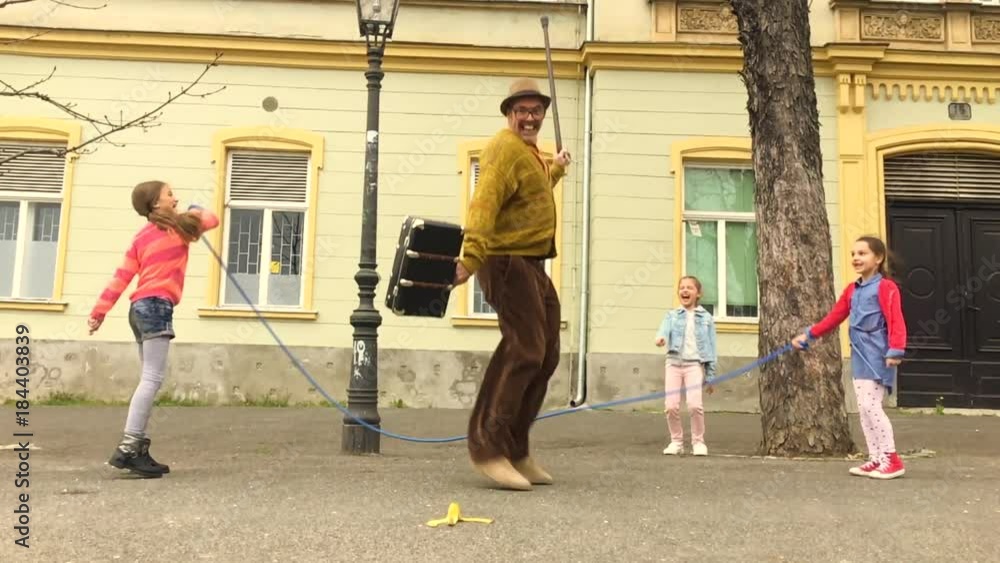 Old man jumping on a skipping rope with three girls in the street. Old man jumping on a skipping rope with three girls in the street.