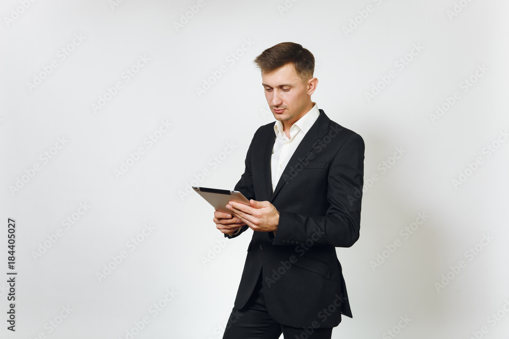 Young successful handsome rich business man in black suit working on modern tablet isolated on white background for advertising. Concept of money, achievement, career and wealth in 25-30 years. Young successful handsome rich business man in black suit working on modern tablet isolated on white background for advertising. Concept of money, achievement, career and wealth in 25-30 years.