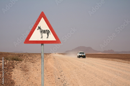  Straßen Warnschild Vorsicht Zebra neben Straße mit Geländewagen.Where: Namib-Naukluft-Region, Namibia. photo